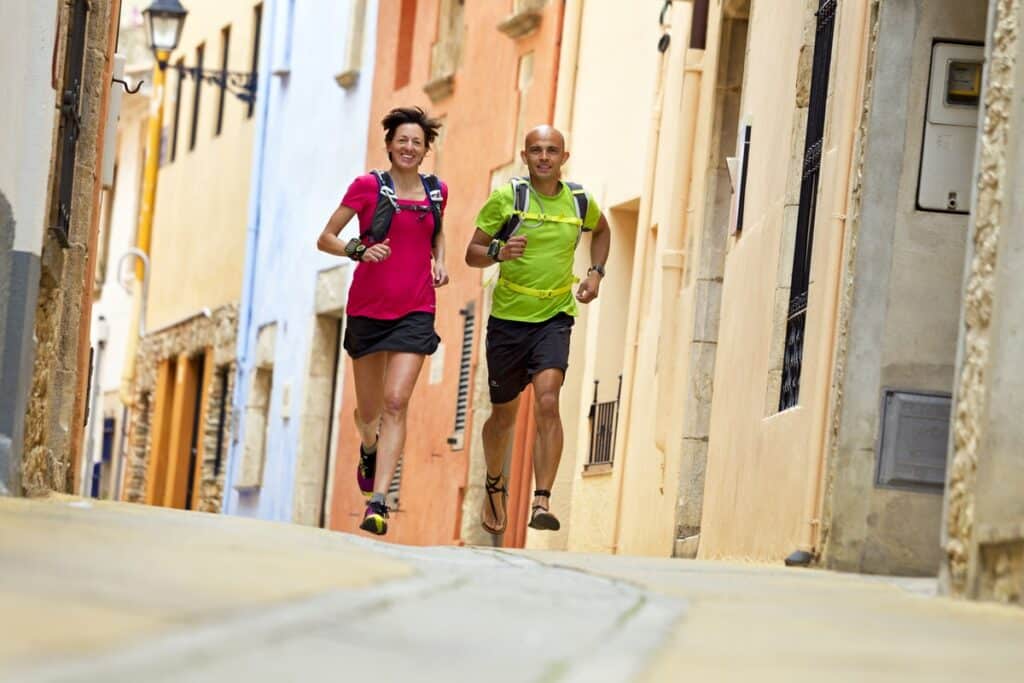 Pablo and Cristina running together down a cobbled street in a Costa Brava village