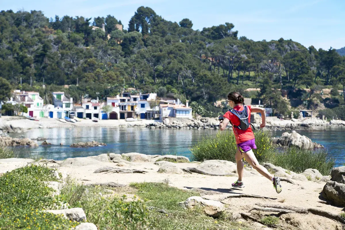 A runner alone on the coast path above a cove of old fishermen's houses on the Costa Brava