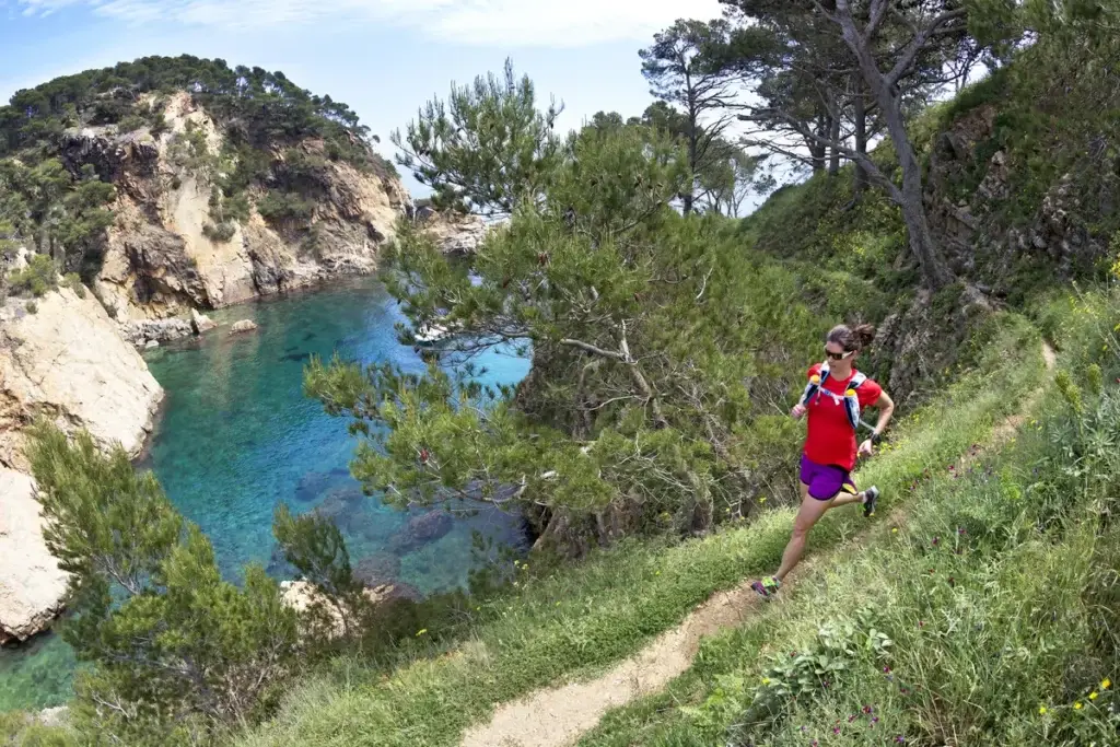 Runner on the Cami de Ronda above a hidden turquoise cove