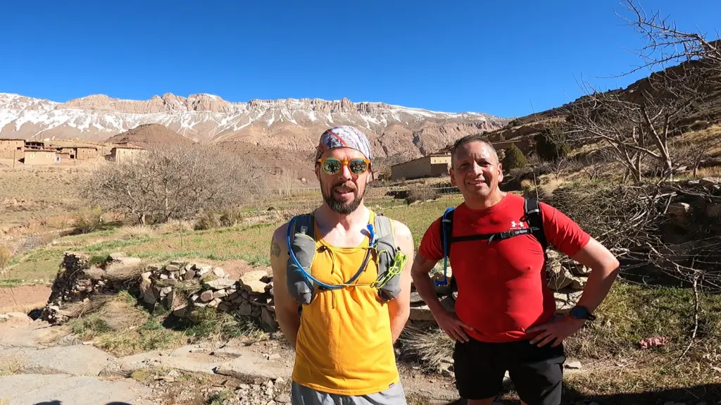 Two runners smiling with a Berber village behind